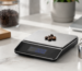 Precision digital scale with calibration weight and coffee beans on a clean countertop